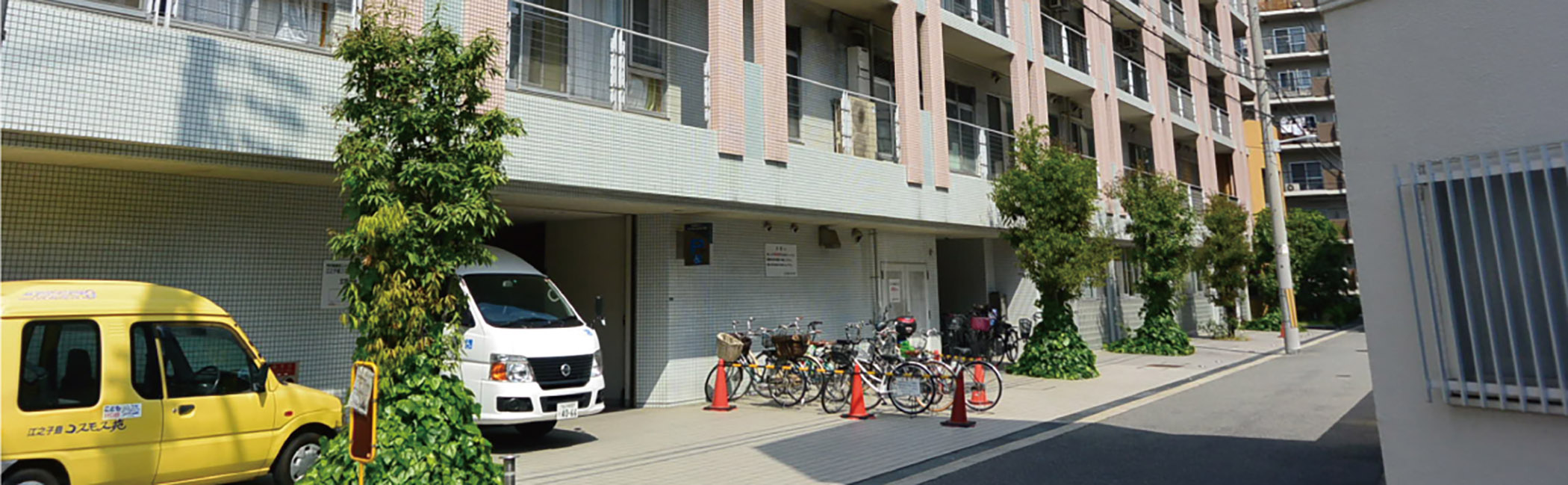 介護施設の建物外観。駐車場とエントランス、自転車置き場が見える。